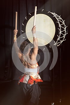 Taiko drummer hits the big drum, back view