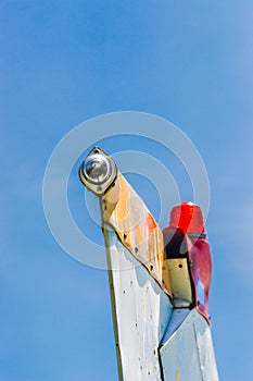 Tail fin, rudder and beacon lights, small single engine airplane with old paint and bright blue sky.