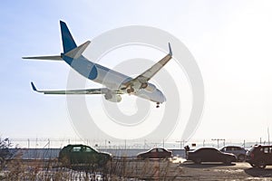Tail view of landing airplane. Aircraft flying over highway. Road with high traffic near airport runway. Type of transport compar