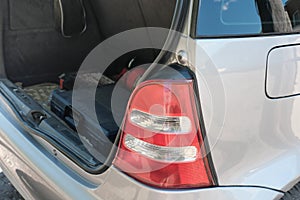 taillight of a silver hatchback car and open trunk with repair tool box. summer travel and car jorney concept