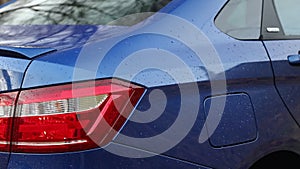 The taillights and the gas tank hatch of a blue modern car.