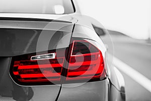 Taillights of a BMW m3 sports car. image black and white, color only taillights