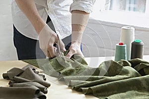 Tailor Cutting Piece Of Cloth At Table In Fashion Studio