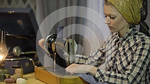 Tailor girl sews cloth with old manual hand sewing machine. Retro seamstress woman works at home or workshop at night