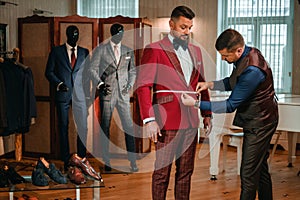Tailor measuring client for custom made suit tailoring.