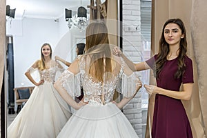 Tailor measuring wedding dress on bride in store