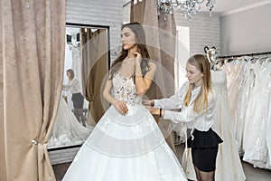 Tailor measuring wedding dress on bride in store