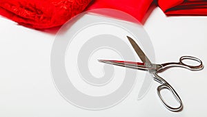 Tailor`s desk. Red luxurious fabric, scissors on a white table background. Space for text