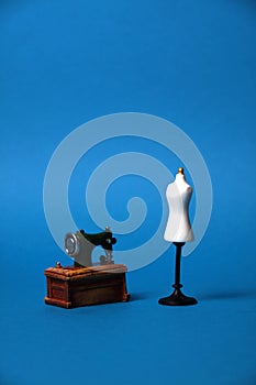 Tailor`s dummy and sewing machine isolated on blue background
