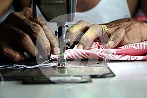 Tailor`s hand sewing a piece of cloth on a sewing machine