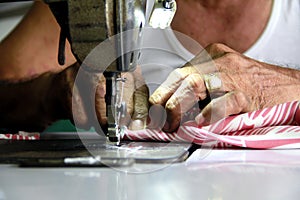 Tailor`s hand sewing a piece of cloth on a sewing machine