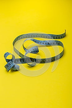 Tailor`s measuring tape on yellow background