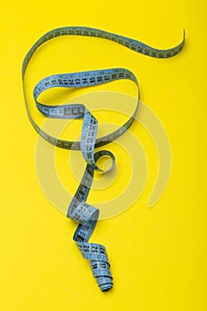 Tailor`s measuring tape on yellow background