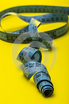 Tailor`s measuring tape on yellow background