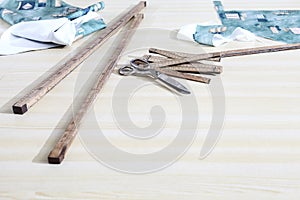 Tailor`s tools, old scissors, wooden meter and ruler on the sartorial work table