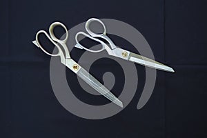 Tailor scissors lie on a dark blue table. The view from the top.
