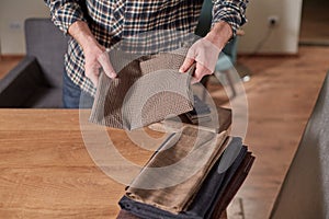Tailor Selects wool from the stack. Young man working as a tailor and using a sewing machine in workshop.
