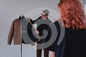 Tailor showing the suit he made. Fashion designer showing an unrecognizable red-haired girl the latest outfit she has