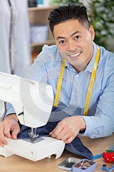 tailor with sitting by sewing machine at workshop