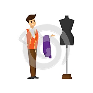 Tailor standing with cut of fabric and measuring tape and pointing hand at mannequin