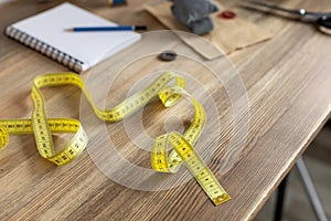 Tailor tape measure and sewing accessories with supplies at table. Concept of clothes atelier