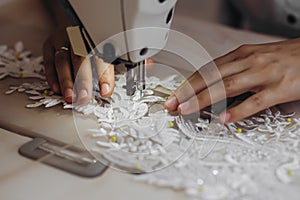 A tailor is using machine for perfecting the white ornament