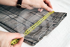 Tailor using a measure tape to measure width of pants