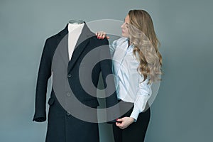 Tailor woman checking new sewn winter jacket on mannequin.