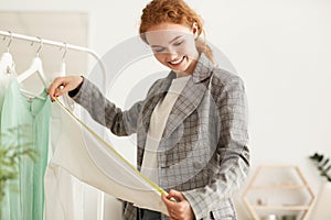 Tailor woman measuring shirt sleeve using tape meter