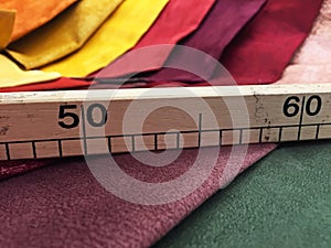 Tailor wooden ruler on colorful fabrics background