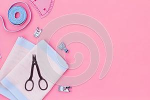 Tailor work place with thread, scissors, fabric. Sewing as hobby. Pink background top view space for text