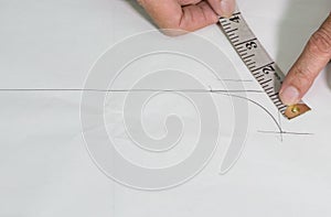 Tailor working with paper as draft of design, close up