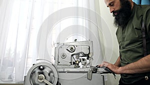 A Tailor works on his eyelet buttonhole machine.