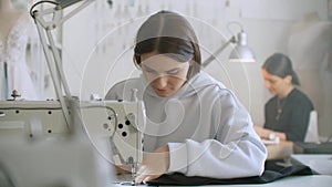 Tailoring of clothes. Seamstresses at work in workshop sewing clothes on sewing machine. Dressmakers sews clothes in