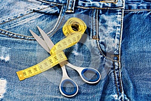 Tailors tools on denim: measure tape wound around metal scissors