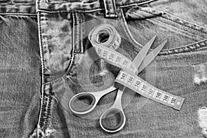 Tailors tools on denim: measure tape wound around metal scissors