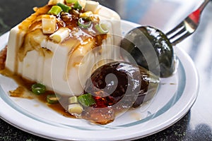 Taiwan`s distinctive famous snacks: thousand-year-old eggs tofupidan tofu in a white plate on stone table, Taiwan Delicacies