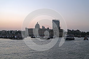 Taj Mahal hotel, Gateway of India and tourist boats in water of Arabian Sea on sunset in Mumbai