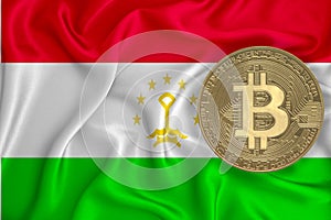 Tajikistan flag, bitcoin gold coin on flag background. The concept of blockchain, bitcoin, currency decentralization in the