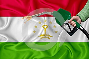 TAJIKISTAN flag Close-up shot on waving background texture with Fuel pump nozzle in hand. The concept of design solutions. 3d