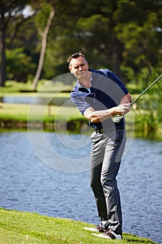 Take aim and let fly. a man taking a swing in a game of golf.