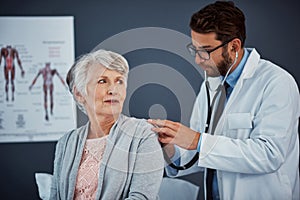 Take another deep breath...a doctor examining a senior patient with a stethoscope in a clinic.