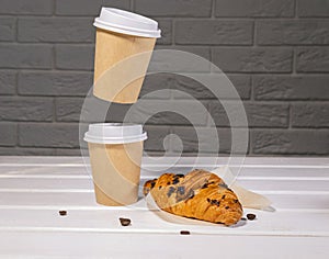 Take Away Coffee in Paper Eco Cup and Fresh Croissant With Chocolate drops on wooden background, Copy Space, Flying food,