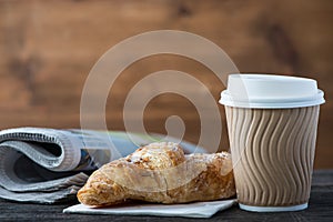 Take away coffee and fresh croissant and newspaper