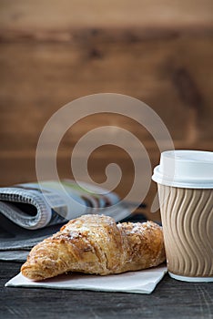 Take away coffee and fresh croissant and newspaper