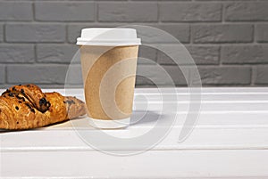 Take Away Coffee in Paper Eco Cup and Fresh Croissant With Chocolate drops on wooden background, Copy Space