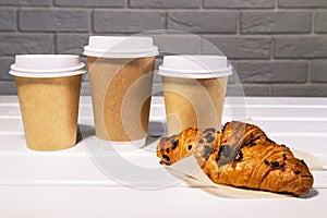 Take Away Coffee in Paper Eco Cup and Fresh Croissant With Chocolate drops on wooden background, Copy Space