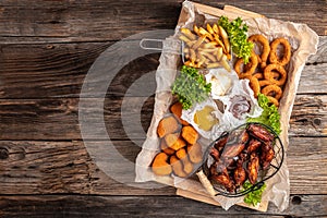 Take away fast food products fried chicken with french fries and nuggets meal, junk food and unhealthy food on a wooden board.