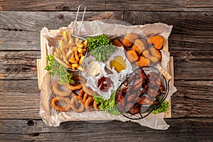 Take away fast food products fried chicken with french fries and nuggets meal, junk food and unhealthy food on a wooden board.