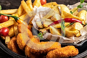 Take away fast food products fried chicken with french fries and nuggets meal, junk food and unhealthy food on a wooden board.